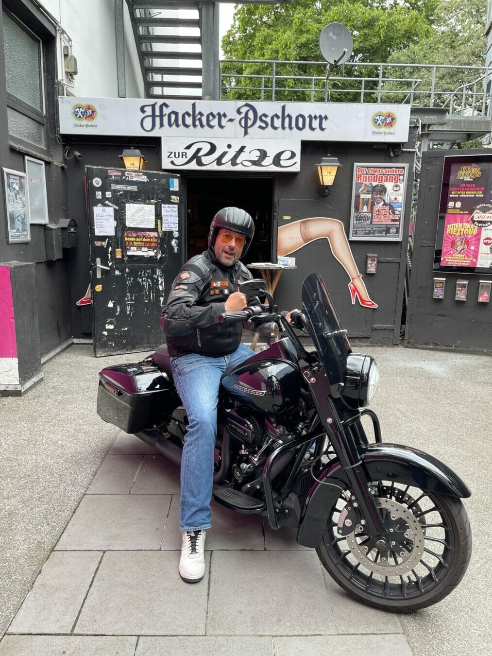 Motorradfahrer vor einem Club mit Werbung.