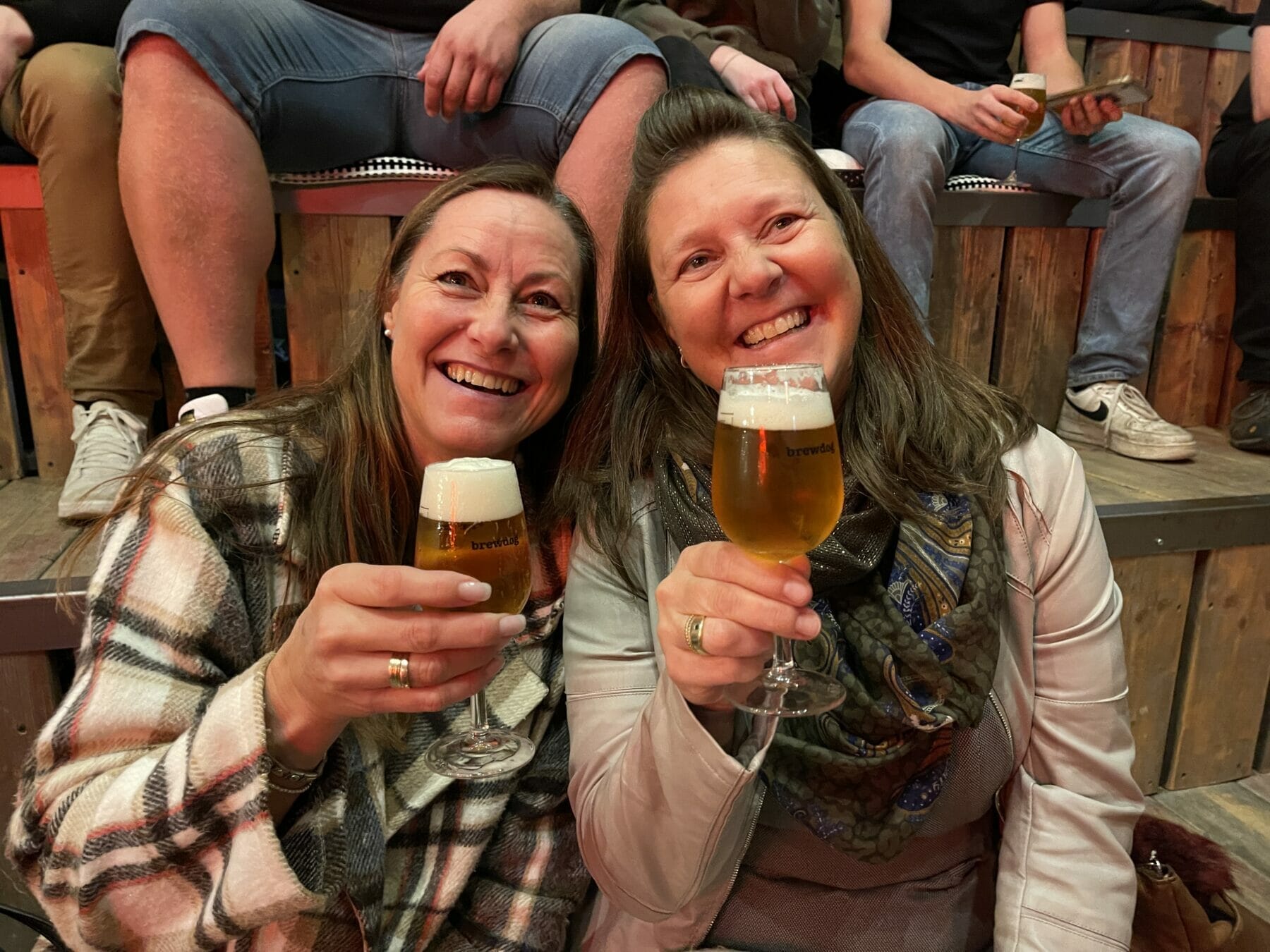 Zwei Frauen stoßen mit Bier an.